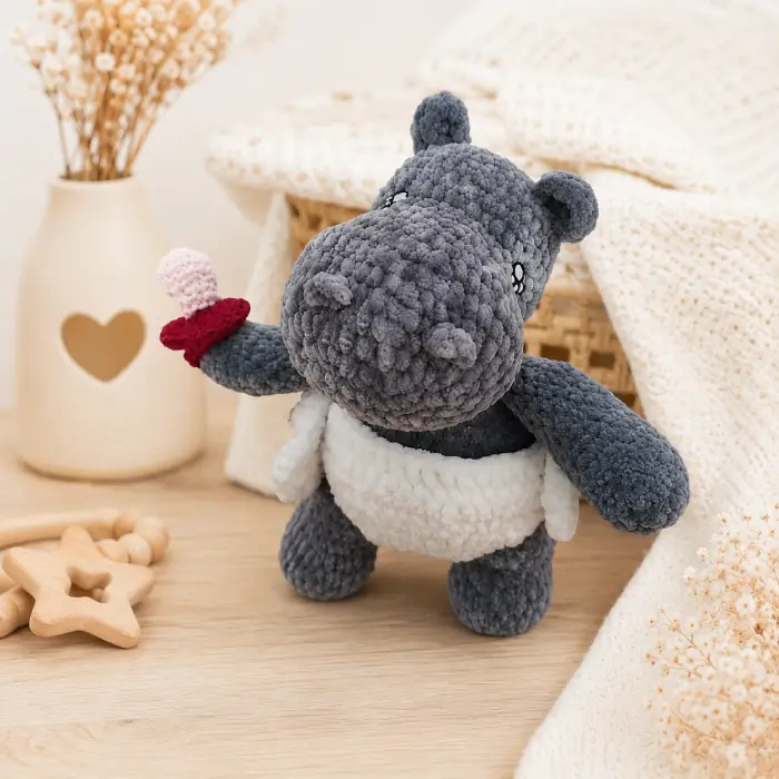 Doudou bébé hippopotame au crochet dans une chambre de bébé Doudou bébé hippopotame au crochet artisanal posé dans un univers doux de chambre de bébé