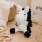 Doudou cheval au crochet artisanal blanc et noir photographié de profil dans une chambre de bébé