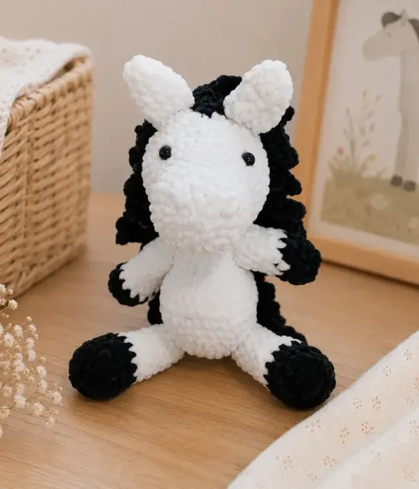 Doudou cheval au crochet artisanal Doudou cheval au crochet artisanal blanc et noir présenté dans une chambre de bébé