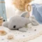 Doudou dauphin au crochet artisanal dans une chambre bébé bord de mer Doudou dauphin au crochet artisanal gris présenté dans une décoration douce inspirée de l'univers marin et des chambres de bébé