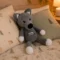 Doudou loup au crochet posé sur un lit d'enfant Doudou loup au crochet gris fait main posé entre deux oreillers sur un lit d'enfant